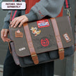 Red, grey, and brown canvas Satchel with plaid lining, featuring a padded laptop pocket, adjustable strap, and magnetic closure. 