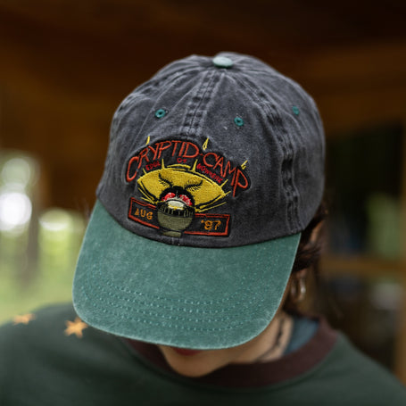 Cotton 6 panel dad-cap in green and black, with 80's camp style, cryptid-themed embroidered.