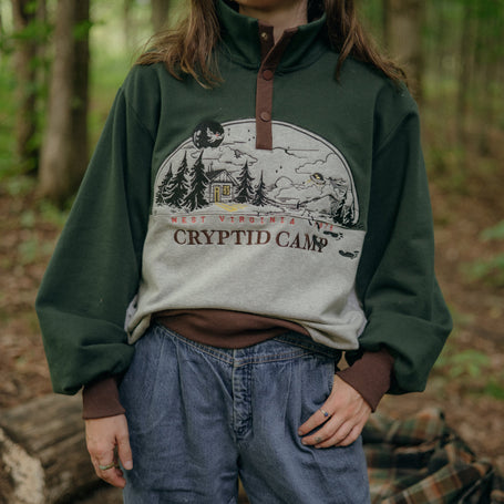 Cozy green, brown, and grey cotton, 3-button, crewneck sweatshirt, featuring a vintage summer camp style embroidered design and cryptid-themed symbols and text.