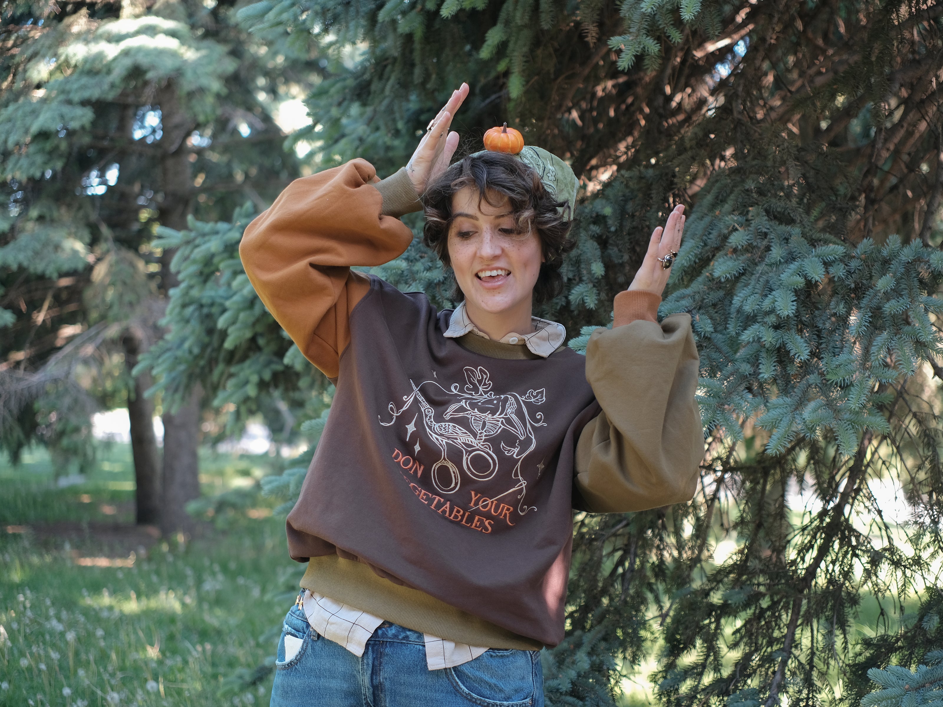 Cozy, oversized, puff-sleeved, cotton crewneck sweater in pumpkin-orange and shades of brown. The sweater features an intricately embroidered design in white and orange, of a pumpkin skeleton, vines, stork scissors, and reads â€œDon Your Vegetablesâ€.