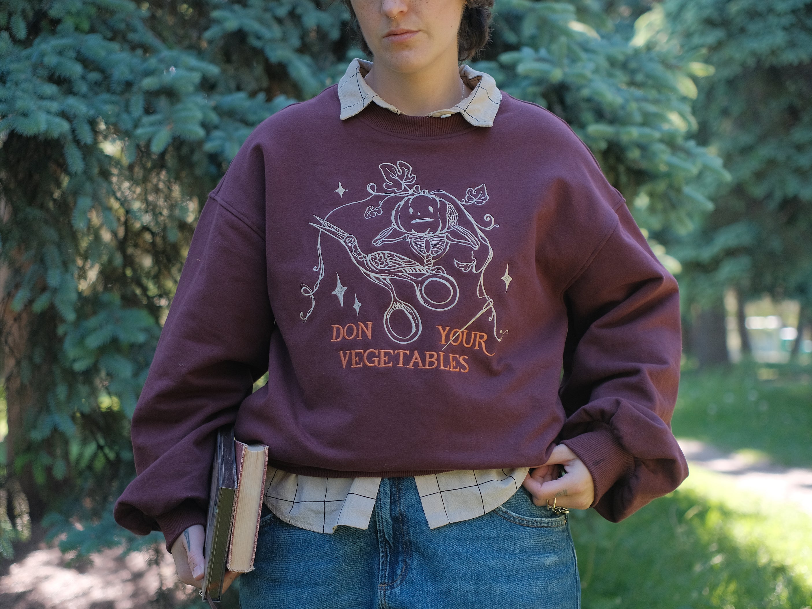 Cozy, oversized, puff-sleeved, cotton with fleece-lining, crewneck sweater in burgundy. The sweater features an intricately embroidered design in white and orange, of a pumpkin skeleton, vines, stork scissors, and reads â€œDon Your Vegetablesâ€.