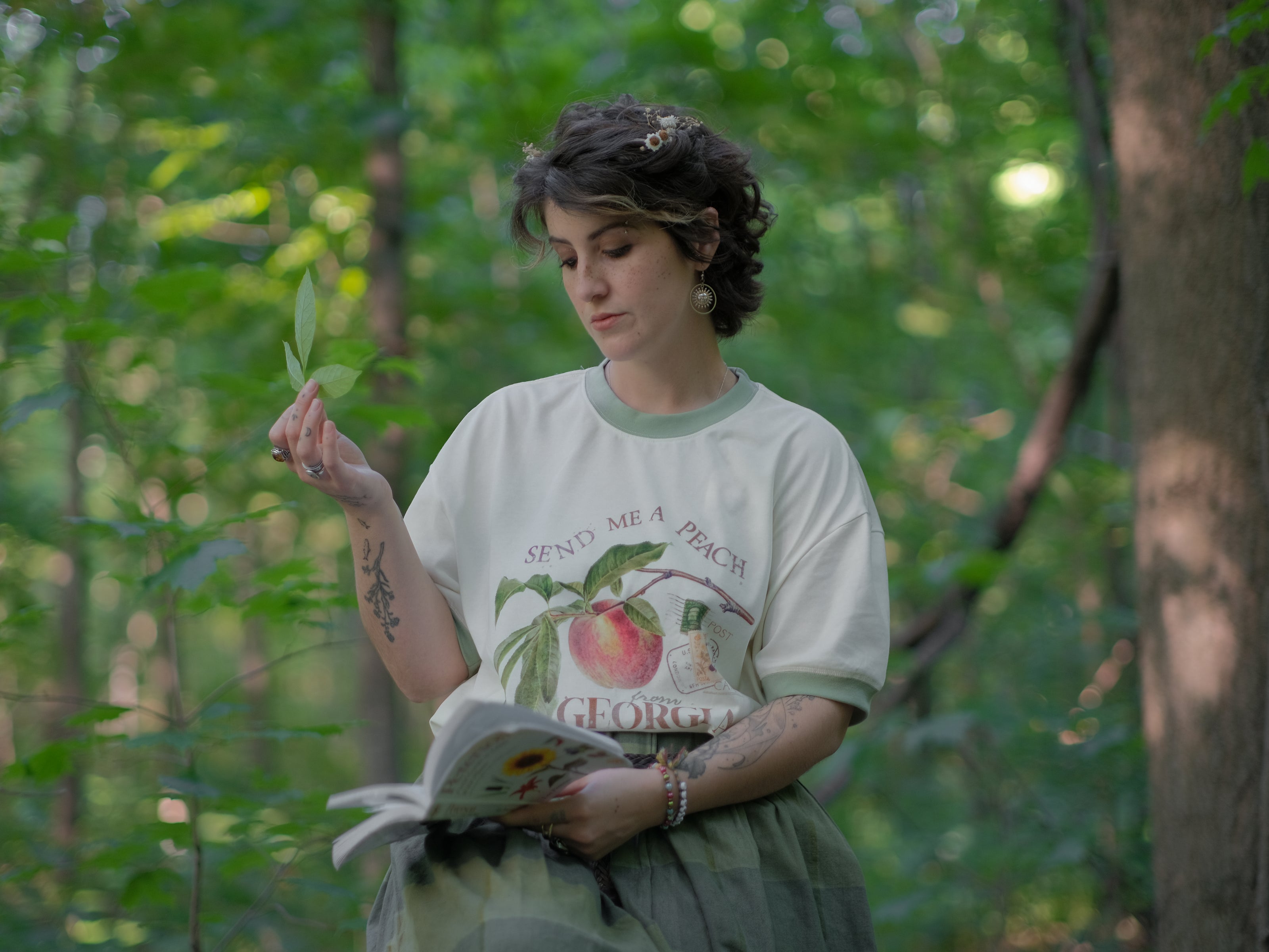 A cotton, vintage-style ringer t-shirt, in shades of soft cream and sage. The shirt is printed with a faded vintage peach design with postage stamps, and reads â€œsend me a peach from Georgiaâ€.