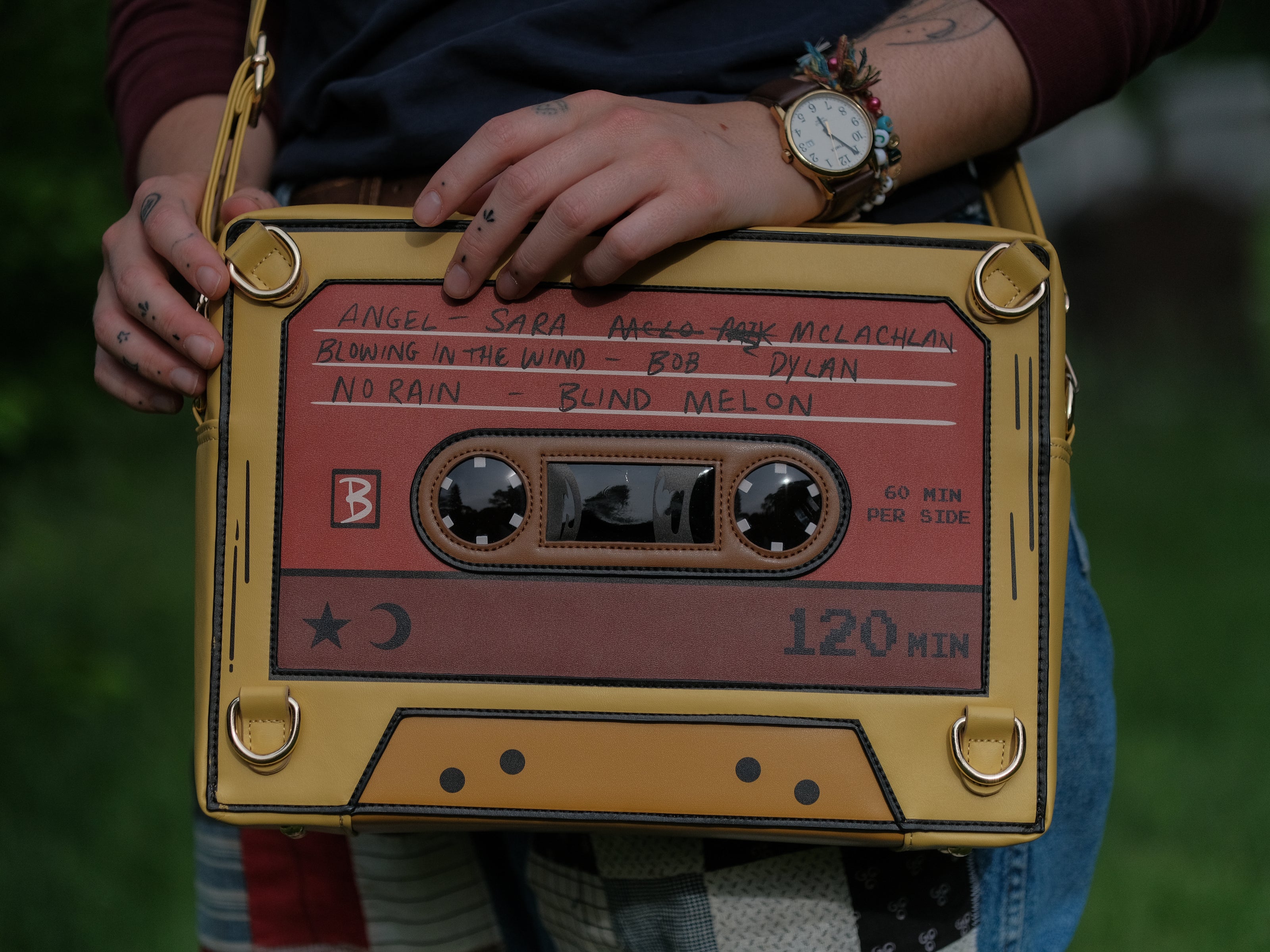 Orange and yellow backpack/satchel, designed to resemble a mix-tape, featuring the classic tape shape, and reads “For Sarah”. The bag includes 2 adjustable backpack straps and 1 adjustable cross-body strap, and features two inner pockets, a padded section, and pen straps. Inner fabric is custom-printed with a stain-resistant fabric.