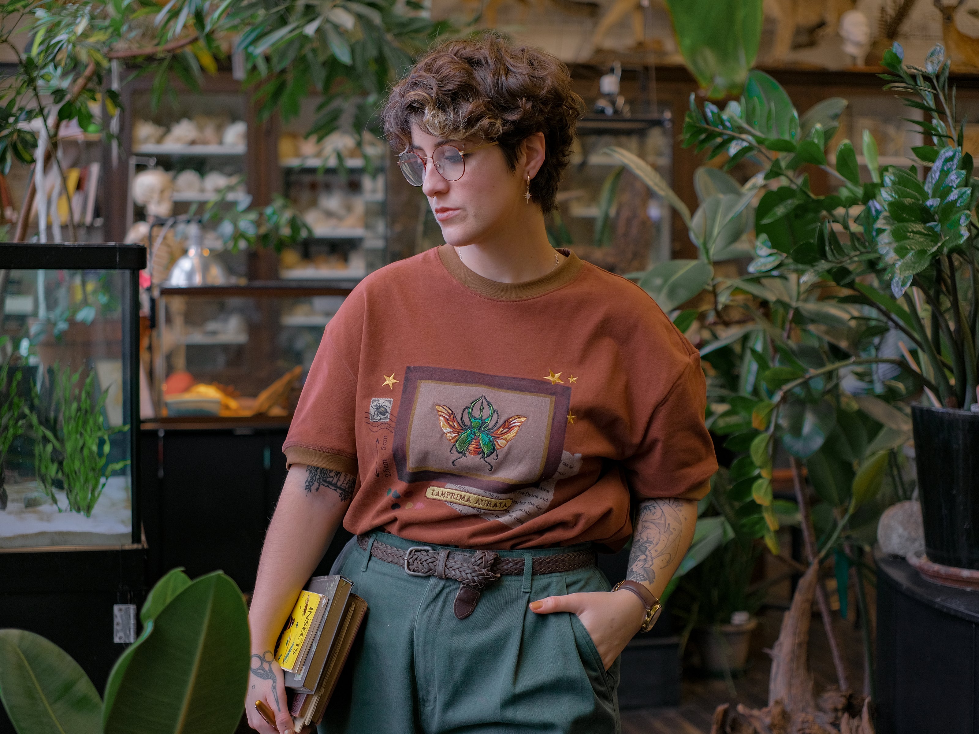 A rusty, vintage orange cotton T-shirt featuring an embroidered stag-horn beetle design framed with vintage-style details, handwritten notes, celestial accents, and latin nomenclature.
