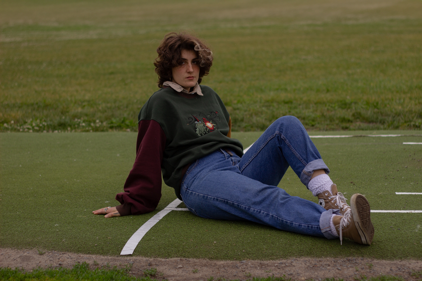 Cozy, oversized, puff-sleeved, color-blocked, cotton crewneck sweater in forest green, with burgundy, and mustard coloured sleeves. The sweater features an intricately embroidered design of a green frog with a red wizard hat and a red lantern on the chest.