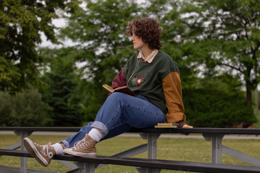 Cozy, oversized, puff-sleeved, color-blocked, cotton crewneck sweater in forest green, with burgundy, and mustard coloured sleeves. The sweater features an intricately embroidered design of a green frog with a red wizard hat and a red lantern on the chest.