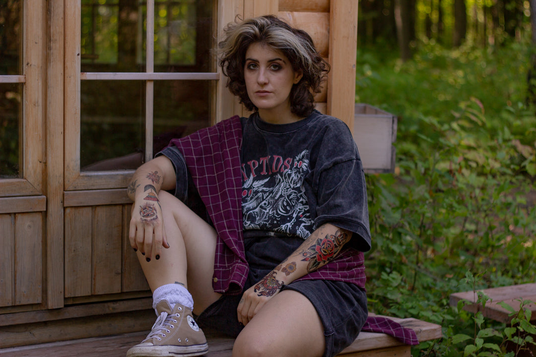 Black acid-washed oversized 80's style cotton band t-shirt with a vintage-style graphic depicting cryptids, including Bigfoot and Mothman, along with the bold text 'Cryptids On Tour' in red and white, and a list of shows across various locations and dates on the back.