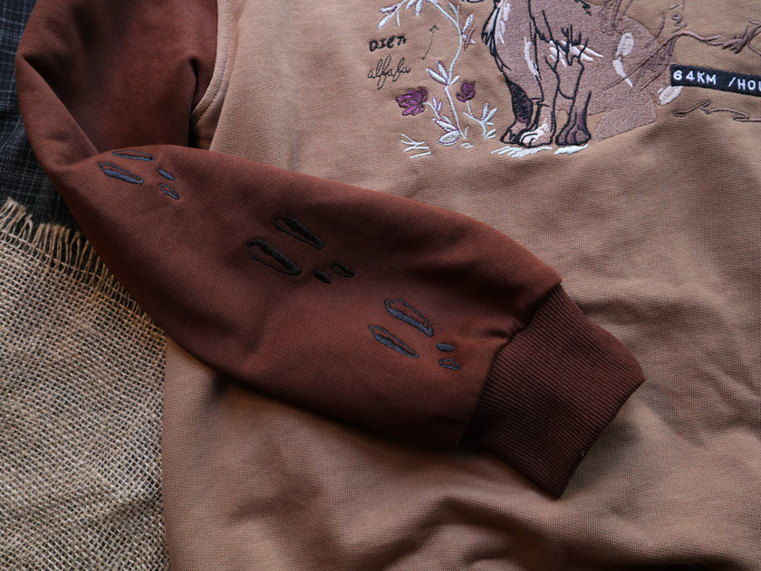 Cozy rust-orange, and peach cotton crewneck sweatshirt, featuring a vintage, embroidered design of the Jackalope with cryptid summer camp-themed symbols and text.