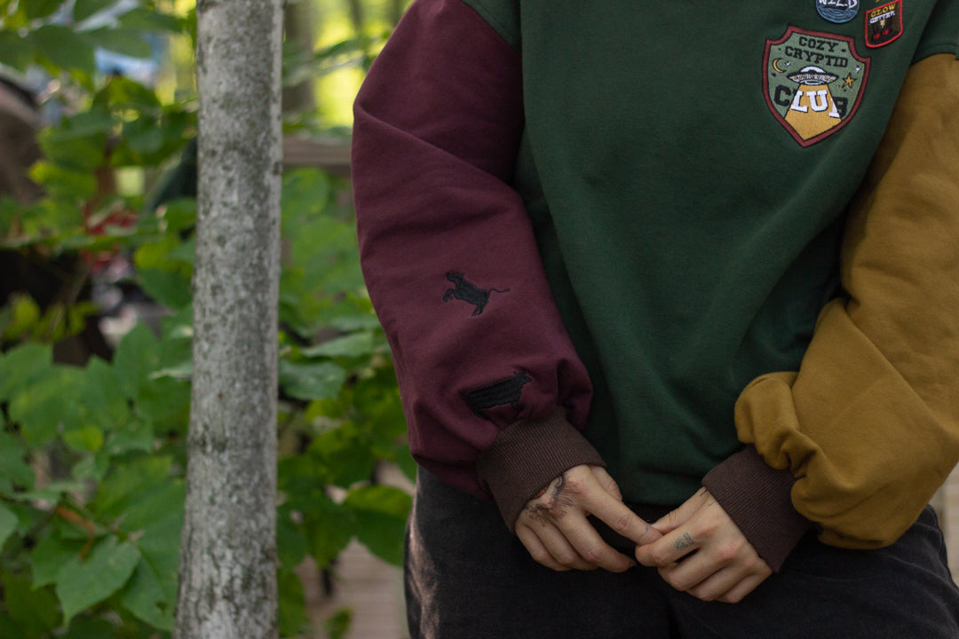 Cozy Forest green, deep yellow, and burgundy cotton crewneck sweatshirt, featuring a vintage, 80â€™s summer camp style embroidered â€œiron onâ€ patches, designed with cryptid-themed symbols and text.