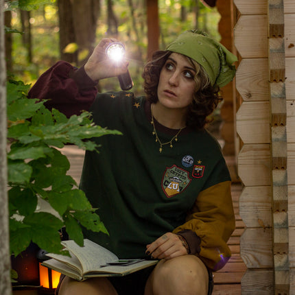 Cozy Forest green, deep yellow, and burgundy cotton crewneck sweatshirt, featuring a vintage, 80’s summer camp style embroidered “iron on” patches, designed with cryptid-themed symbols and text.