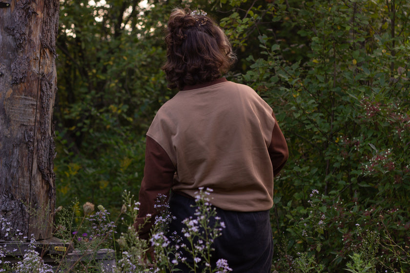 Cozy rust-orange, and peach cotton crewneck sweatshirt, featuring a vintage, embroidered design of the Jackalope with cryptid summer camp-themed symbols and text.