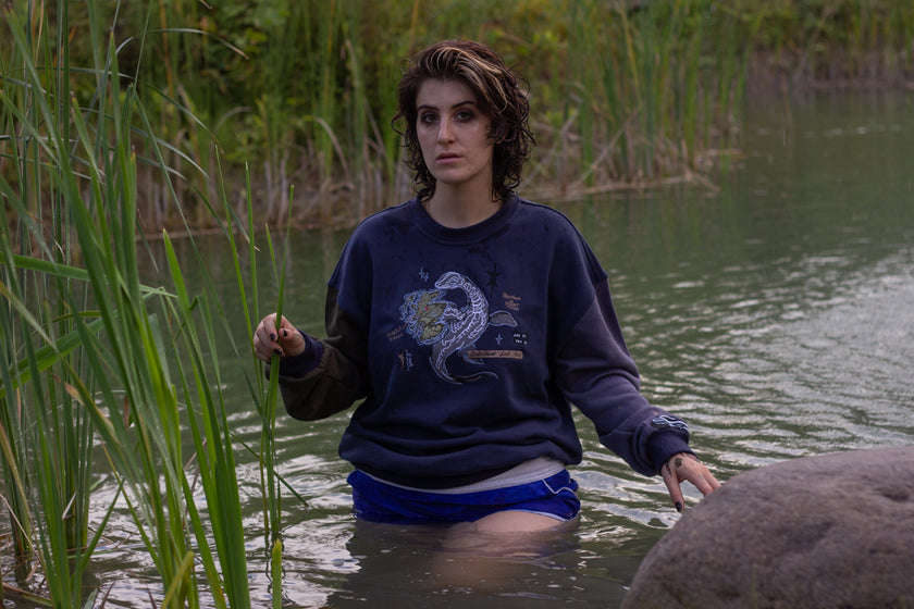 Cozy navy and fog-blue cotton crewneck sweatshirt, featuring a vintage, 80â€™s summer camp style embroidered design of the Mothman with cryptid-themed symbols and text.