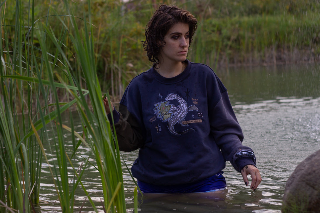Cozy navy and fog-blue cotton crewneck sweatshirt, featuring a vintage, 80â€™s summer camp style embroidered design of the Mothman with cryptid-themed symbols and text.