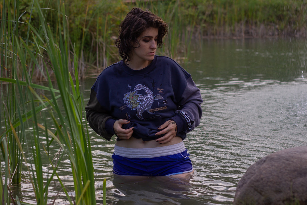 Cozy navy and fog-blue cotton crewneck sweatshirt, featuring a vintage, 80â€™s summer camp style embroidered design of the Mothman with cryptid-themed symbols and text.