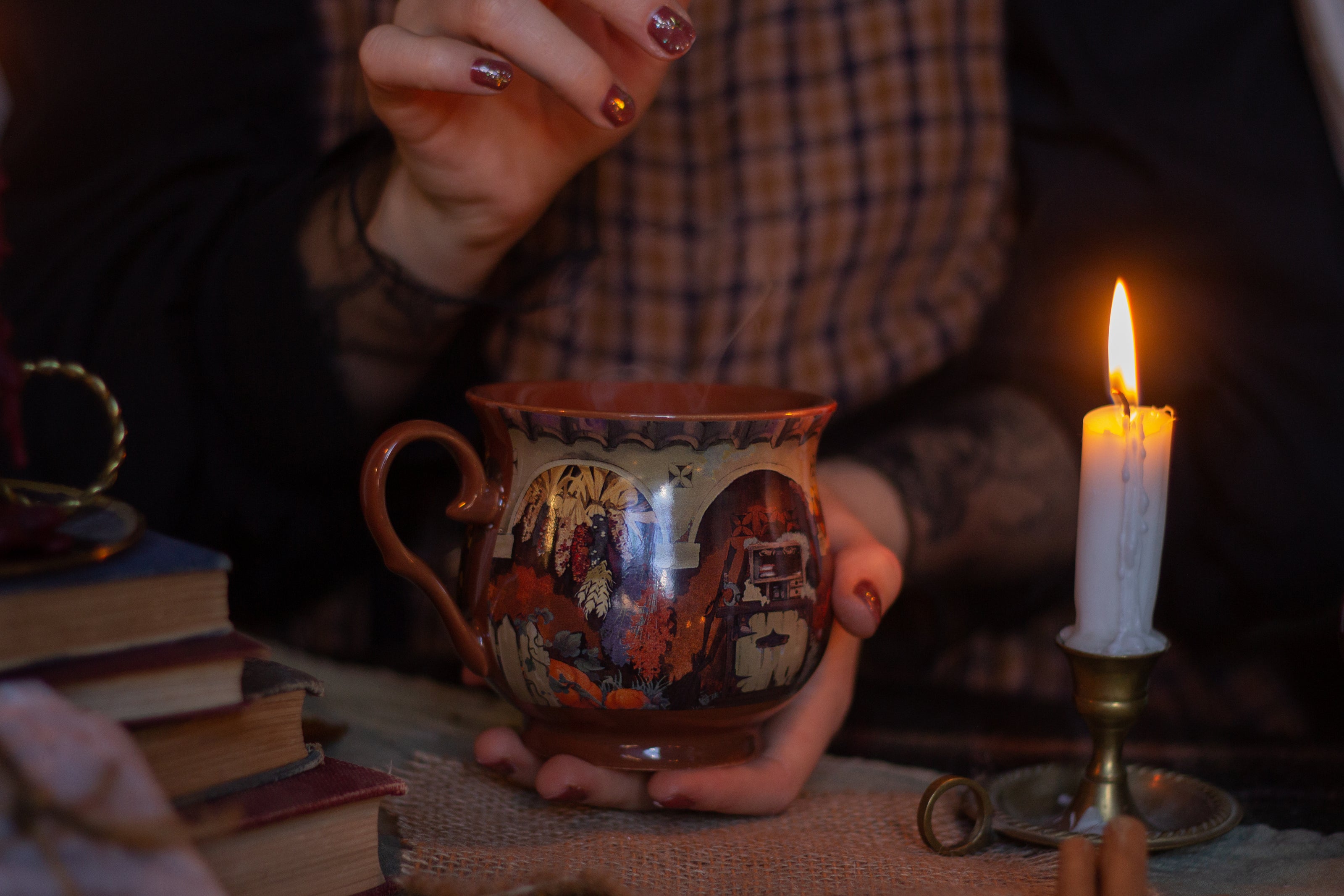 Two intricately designed witches cottage ceramic mugs, featuring vibrant seasonal and whimsical artwork. The top mug showcases an autumnal theme with pumpkins and fall foliage, while the bottom mug highlights an autumnal evening scene with a full moon, a prowling cat, and dark, enchanting colors.