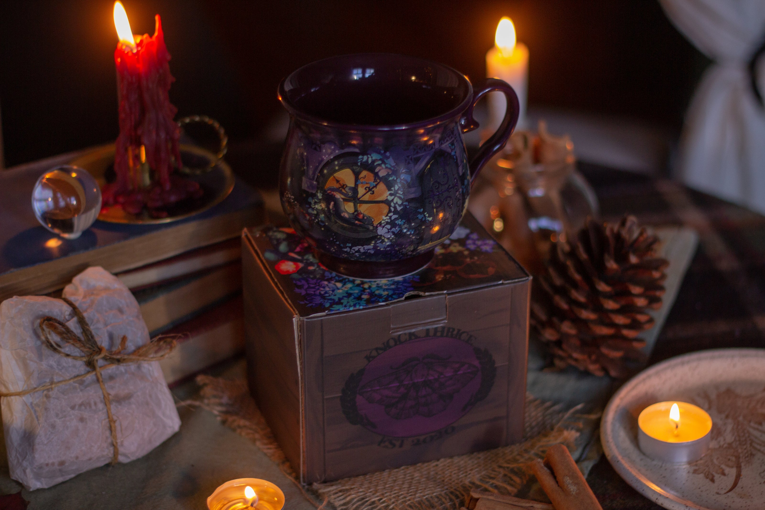 Two intricately designed witches cottage ceramic mugs, featuring vibrant seasonal and whimsical artwork. The top mug showcases an autumnal theme with pumpkins and fall foliage, while the bottom mug highlights an autumnal evening scene with a full moon, a prowling cat, and dark, enchanting colors.