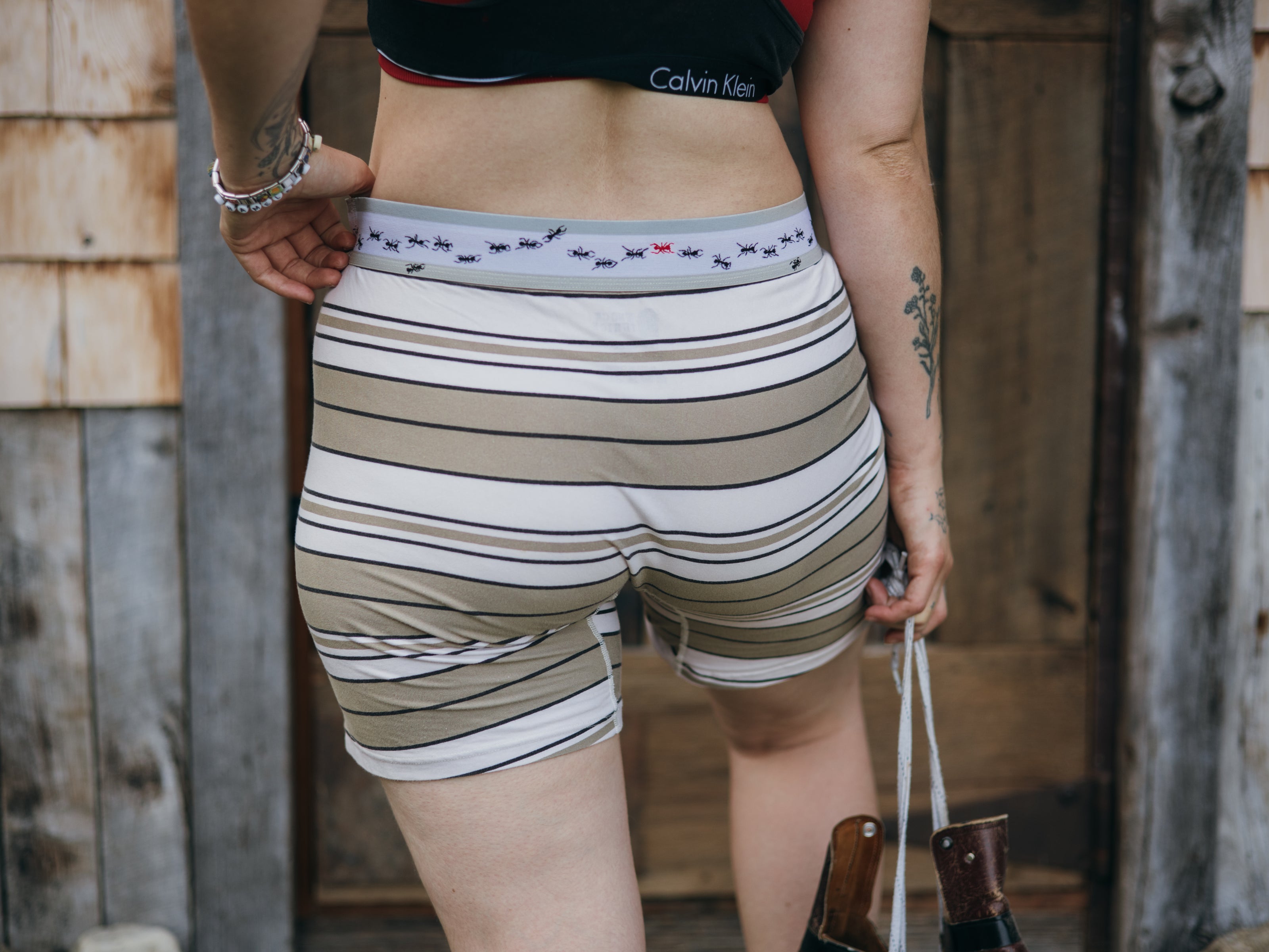 Knock Thrice Knoxers // white, black, and light olive green, striped cotton, fitted boxers. The boxers are mid-high rise,  and have a grey spandex waistband with black and red ants 