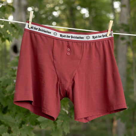 Knock Thrice Knoxers // red cotton, fitted boxers. The boxers are mid-high rise, and have a red and white spandex waistband that pictures a DnD dice and reads "roll for initiative".