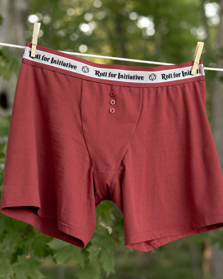 Knock Thrice Knoxers // red cotton, fitted boxers. The boxers are mid-high rise, and have a red and white spandex waistband that pictures a DnD dice and reads "roll for initiative".