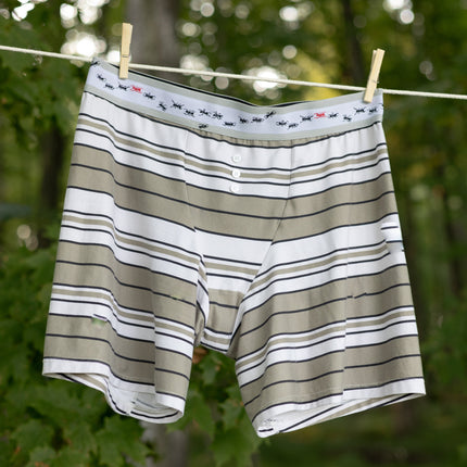 Knock Thrice Knoxers // white, black, and light olive green, striped cotton, fitted boxers. The boxers are mid-high rise,  and have a grey spandex waistband with black and red ants 