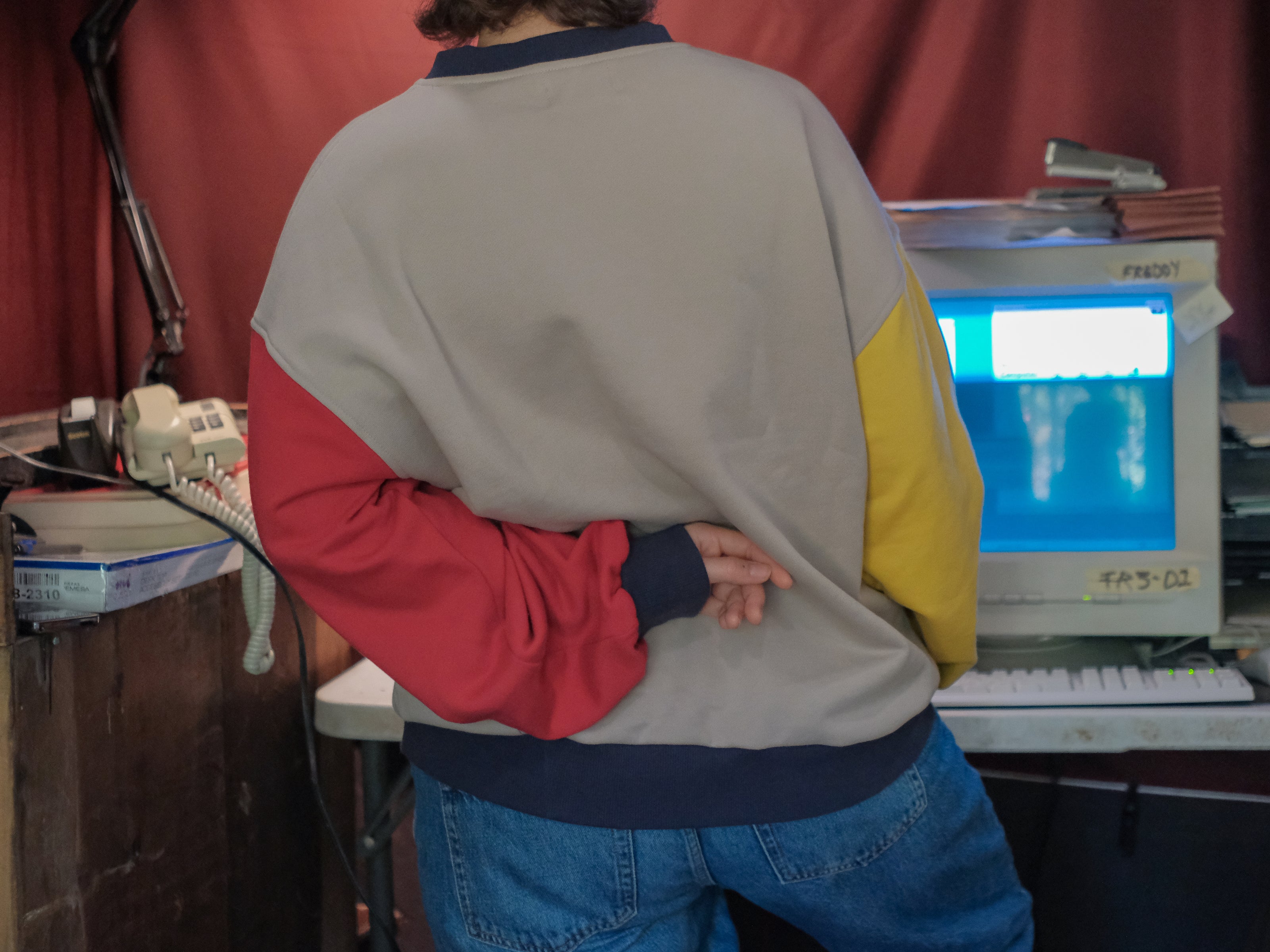 Magnus Protocol, I.T department, cotton jersey crewneck, in beige, with red and yellow colour blocked sleeves. The sweater features vaporwave computer embroidered details, and reads â€œProperty of C. Becherâ€.