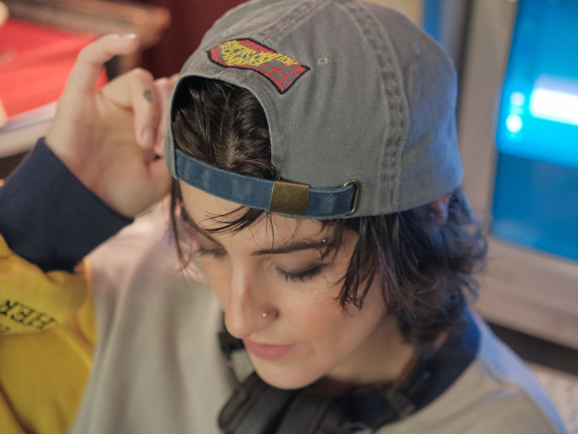 Knock Thrice x Rusty Quill, 100% cotton I.T Department Dad Cap in blue and grey. The hat features an embroidered design of a corrupted computer and glitched OIAR logo, and an adjustable fit.