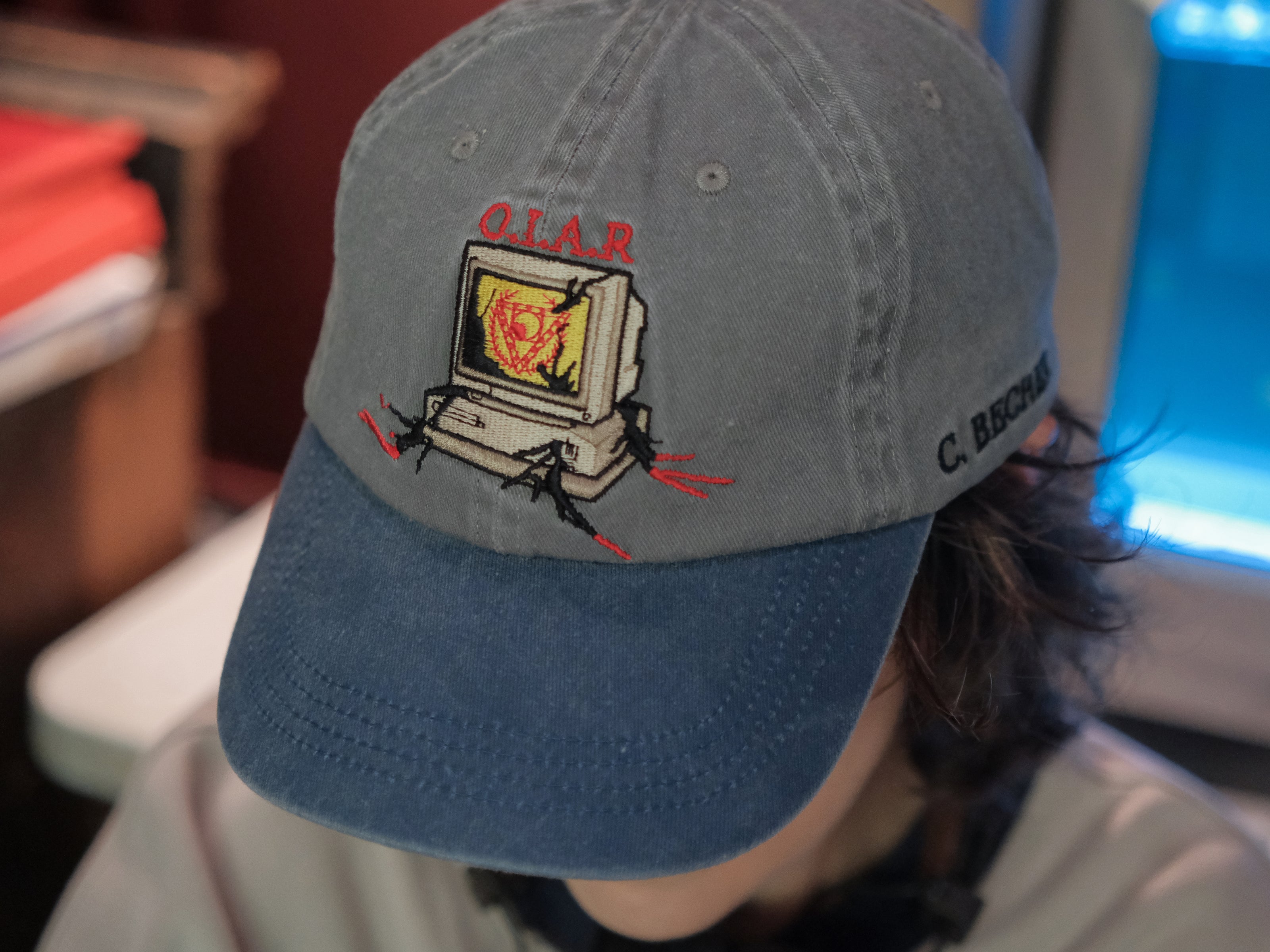 Knock Thrice x Rusty Quill, 100% cotton I.T Department Dad Cap in blue and grey. The hat features an embroidered design of a corrupted computer and glitched OIAR logo, and an adjustable fit.