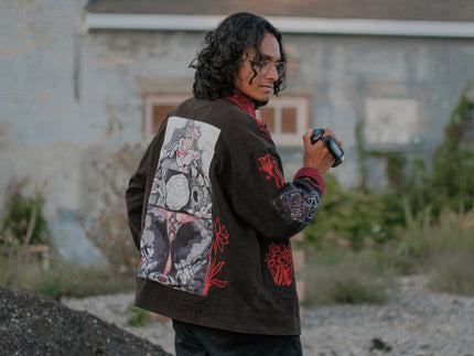 Knock Thrice x Rusty Quill, black fall/spring button-up cotton jacket, with a red corduroy lining. The jacket features both embroidered and patchwork OIAR themed elements, in red, white, and black.