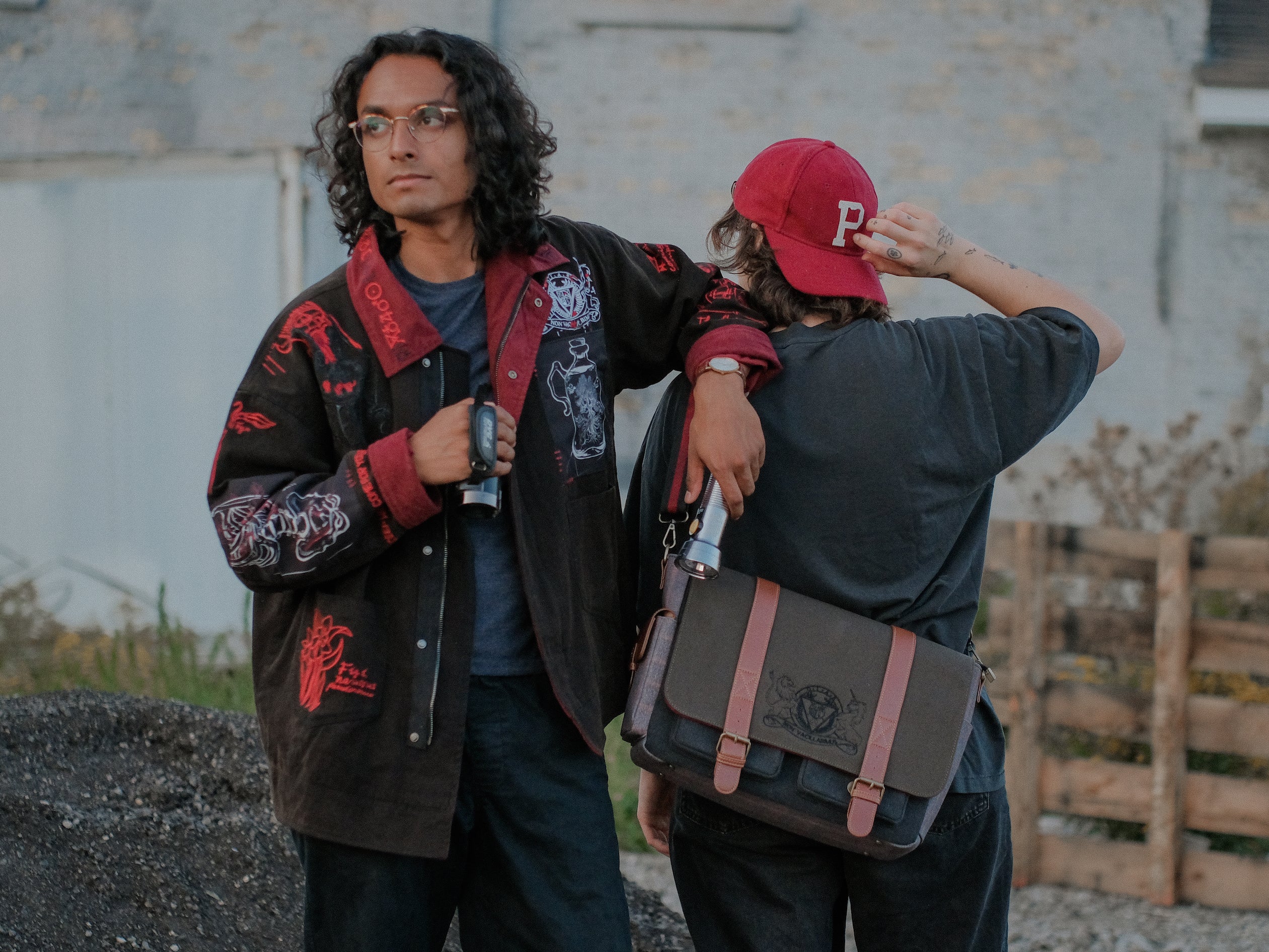 Knock Thrice x Rusty Quill, black fall/spring button-up cotton jacket, with a red corduroy lining. The jacket features both embroidered and patchwork OIAR themed elements, in red, white, and black.