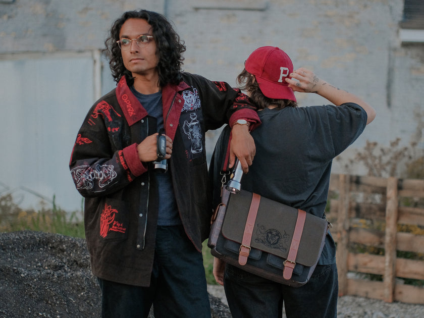 Knock Thrice x Rusty Quill, black fall/spring button-up cotton jacket, with a red corduroy lining. The jacket features both embroidered and patchwork OIAR themed elements, in red, white, and black.
