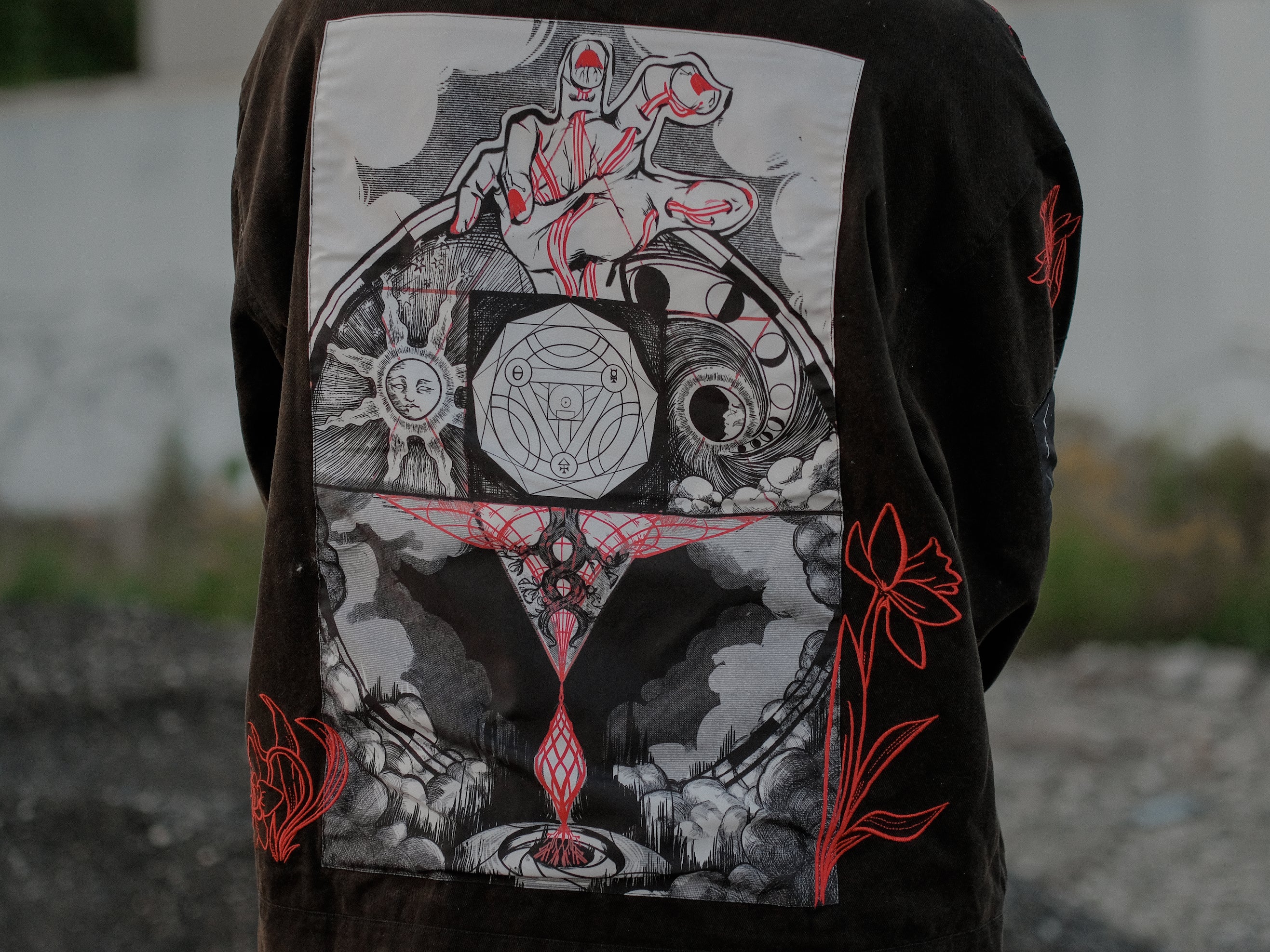 Knock Thrice x Rusty Quill, black fall/spring button-up cotton jacket, with a red corduroy lining. The jacket features both embroidered and patchwork OIAR themed elements, in red, white, and black.