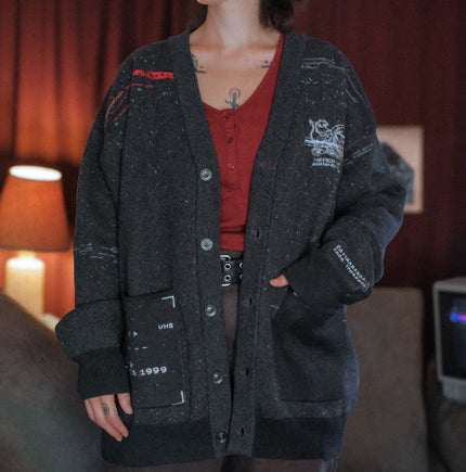 Magnus Protocol, oversized, knit-cardigan, in black. The cardigan is inspired by old cassette tapes, and features embroidered analog details, and the OIAR crest.