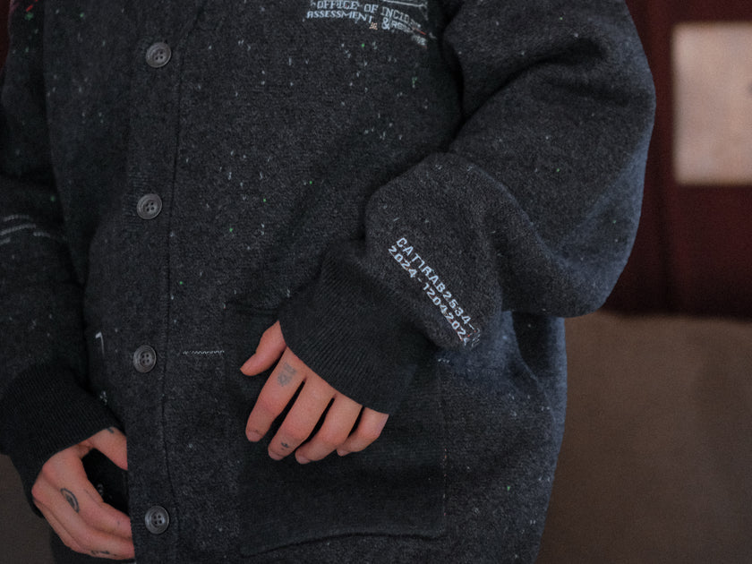 Magnus Protocol, oversized, knit-cardigan, in black. The cardigan is inspired by old cassette tapes, and features embroidered analog details, and the OIAR crest.