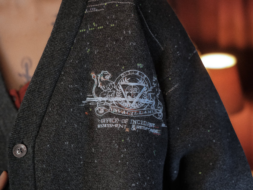 Magnus Protocol, oversized, knit-cardigan, in black. The cardigan is inspired by old cassette tapes, and features embroidered analog details, and the OIAR crest.