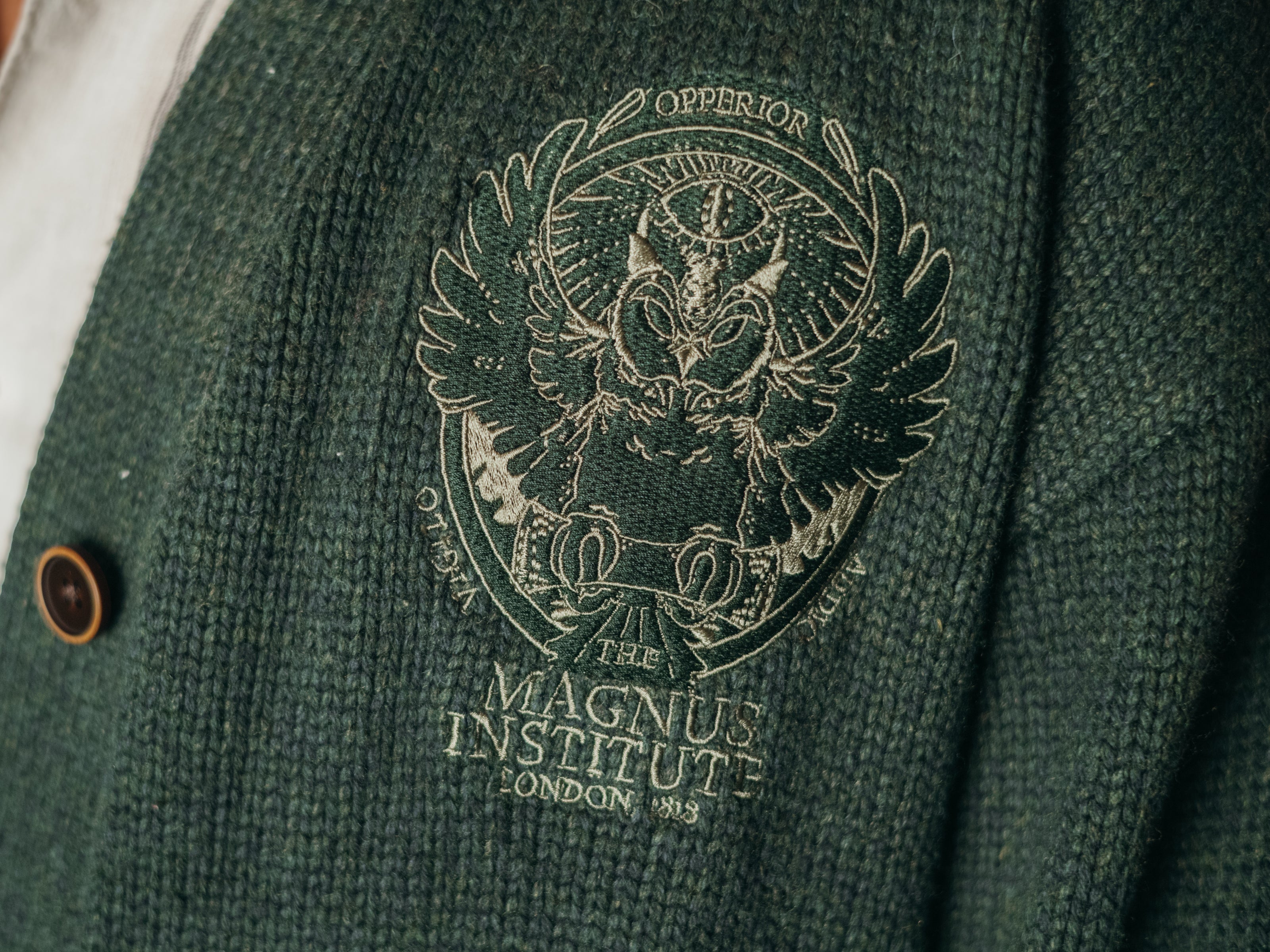 Magnus Archives x Knock Thrice oversized knit cardigan with embroidered details in dark green. Made of 60% Cotton 30% Nylon 10% Wool.