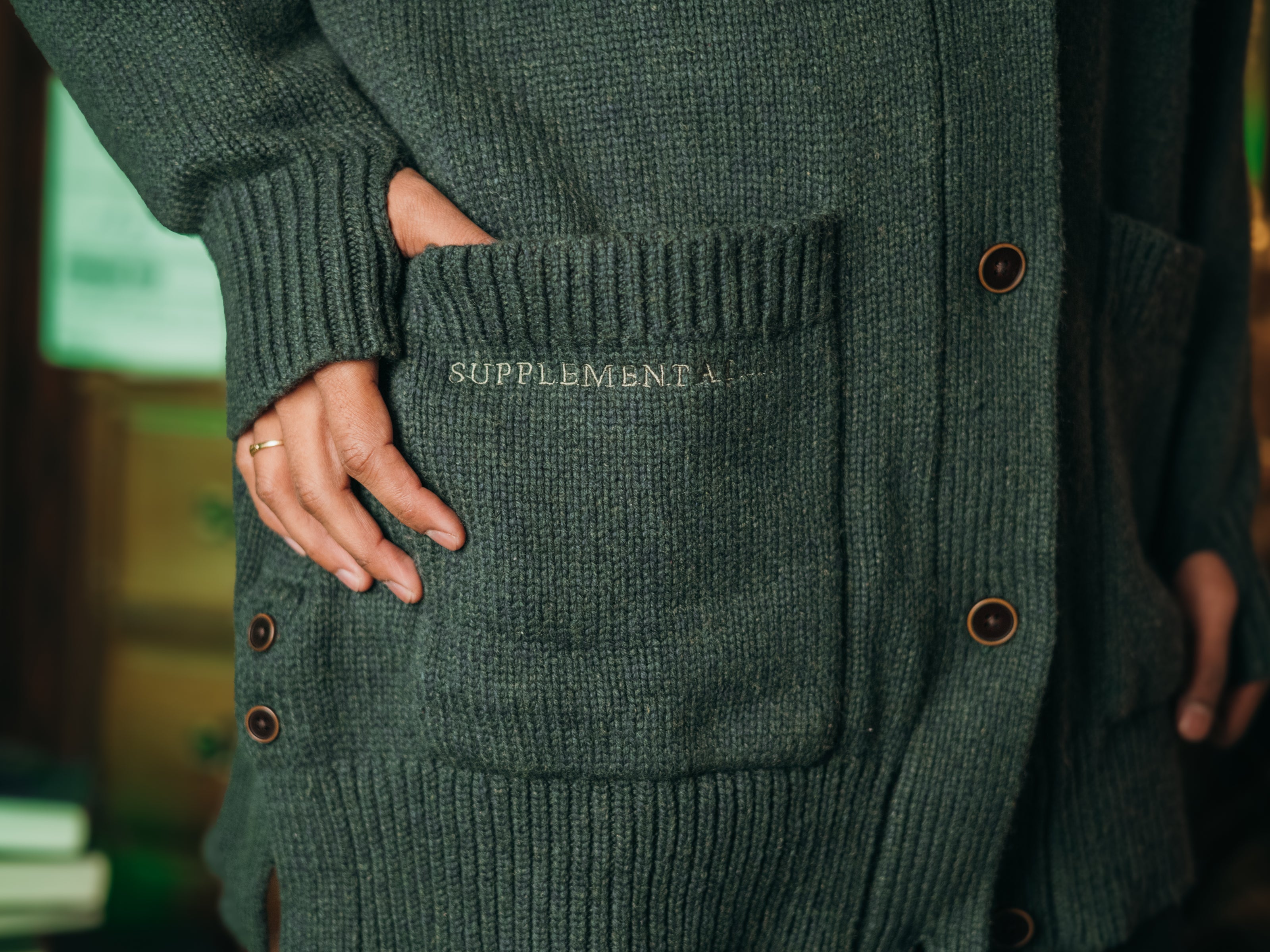 Magnus Archives x Knock Thrice oversized knit cardigan with embroidered details in dark green. Made of 60% Cotton 30% Nylon 10% Wool.
