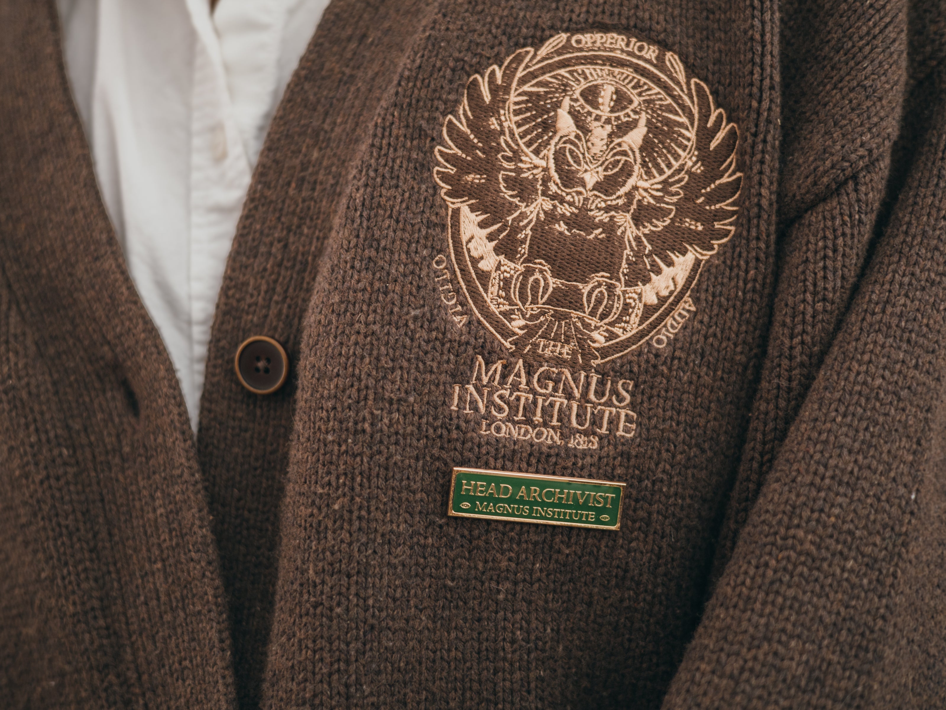 Magnus Archives x Knock Thrice green and gold enamel lapel pin with eye details.