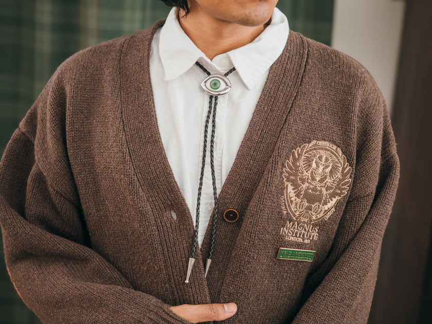 Magnus Archives x Knock Thrice adjustable, leather green-eye bolo tie, with silver details.