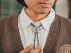 Magnus Archives x Knock Thrice adjustable, leather green-eye bolo tie, with silver details.