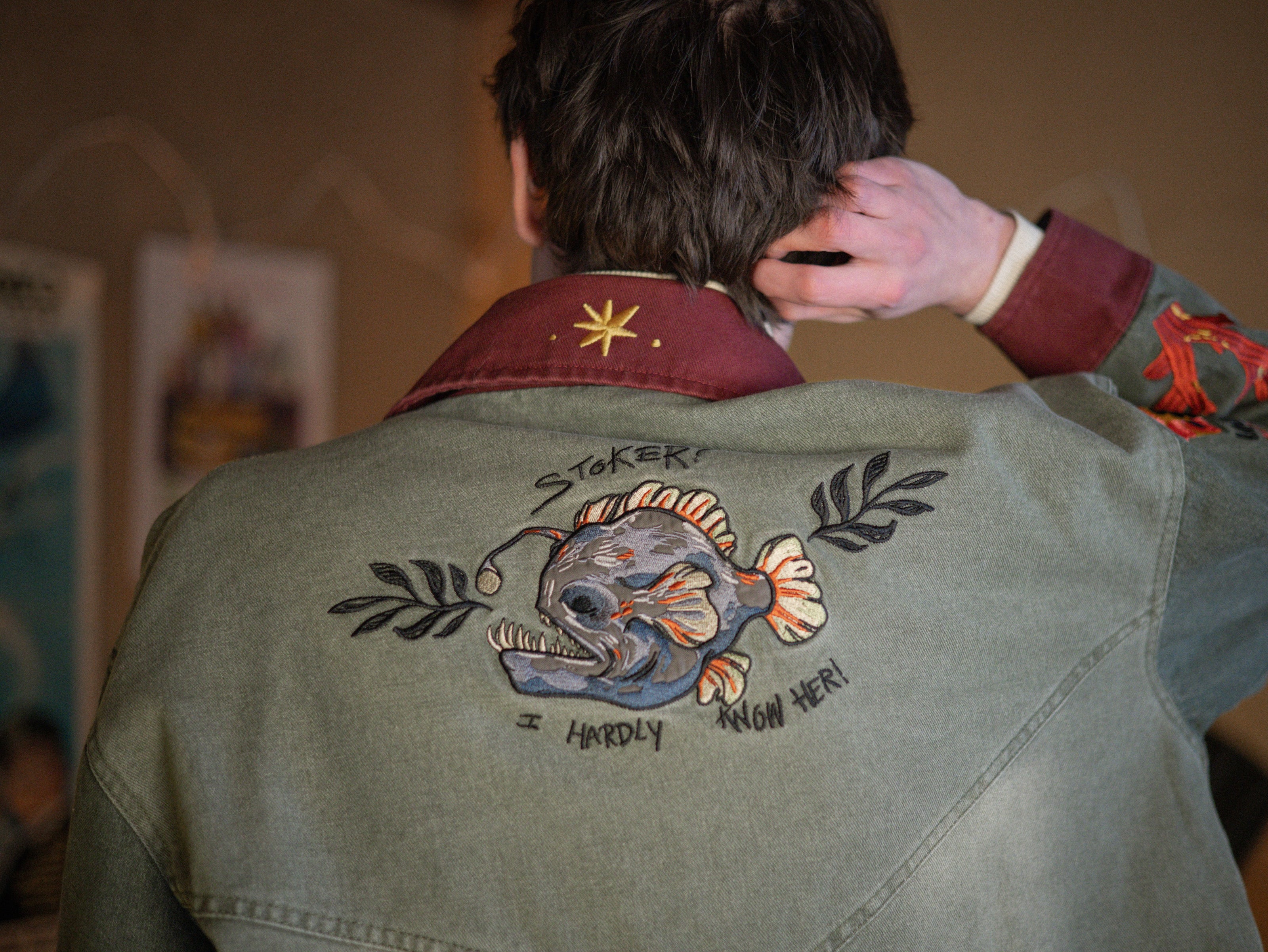 Knock Thrice x Rusty Quill, black fall/spring button-up cotton jacket. The jacket features both embroidered and patchwork OIAR themed elements, in red, and green.