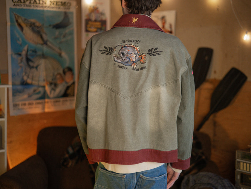 Knock Thrice x Rusty Quill, black fall/spring button-up cotton jacket. The jacket features both embroidered and patchwork OIAR themed elements, in red, and green.