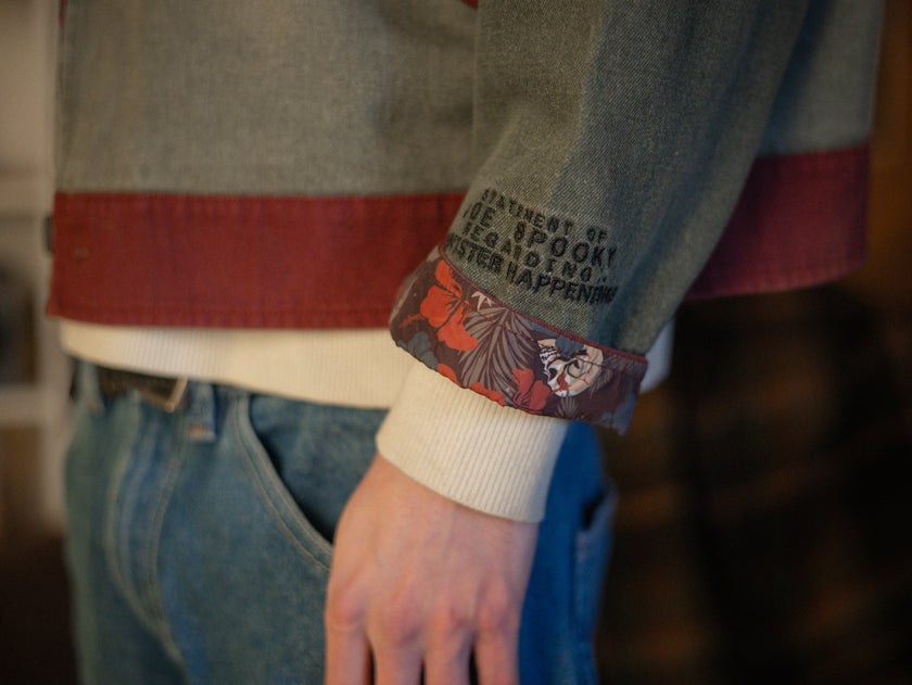 Knock Thrice x Rusty Quill, black fall/spring button-up cotton jacket. The jacket features both embroidered and patchwork OIAR themed elements, in red, and green.