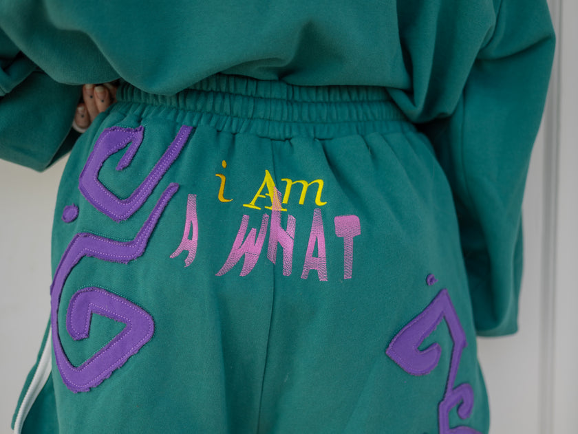 Magnus Archives x Knock Thrice “I’m a What” long shorts in green and purple, 100% cotton graphic shorts with embroidered details